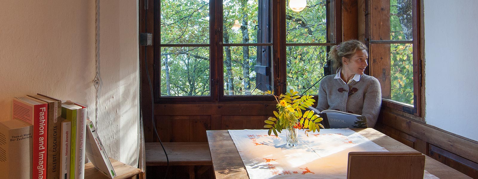 eine Dame sitzt am hellen Esstisch der Ferienwohnung Luise des Hotel Briol in Barbian